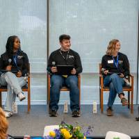 Group of students sitting between Kala Gibson and President Mantella as part of panel on stage